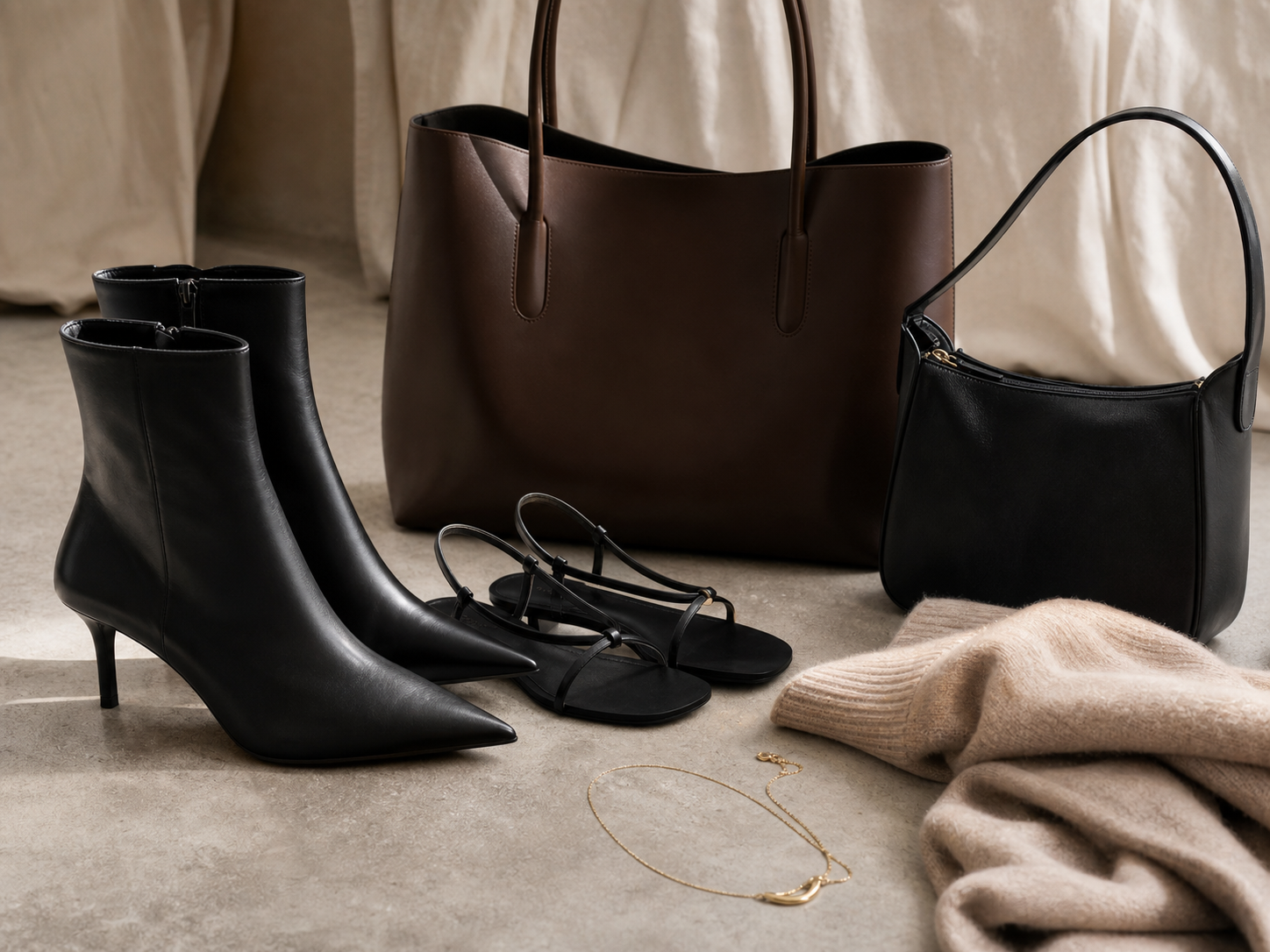 Fashion detail image with pointed ankle boots, strappy sandals, structured tote, shoulder bag, cashmere knit, and fine gold necklace